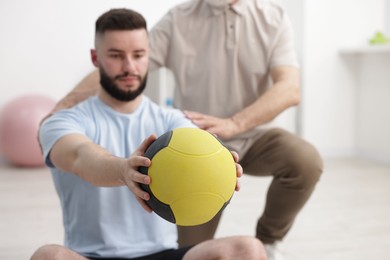 Photo of Doctor and patient exercising with medicine ball in clinic
