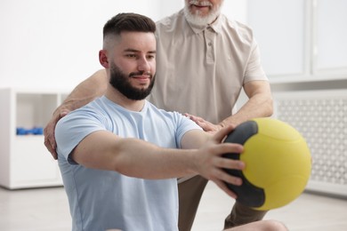 Photo of Doctor and patient exercising with medicine ball in clinic