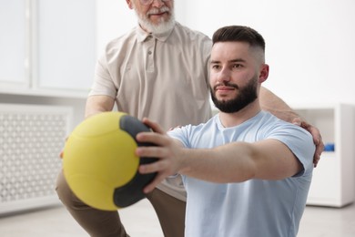 Photo of Doctor and patient exercising with medicine ball in clinic