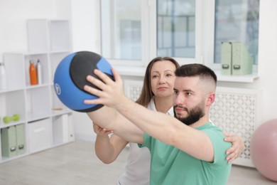 Photo of Doctor and patient exercising with medicine ball in clinic