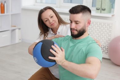 Photo of Doctor and patient exercising with medicine ball in clinic, space for text