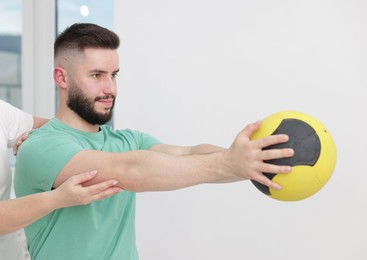 Photo of Doctor and patient exercising with medicine ball in clinic