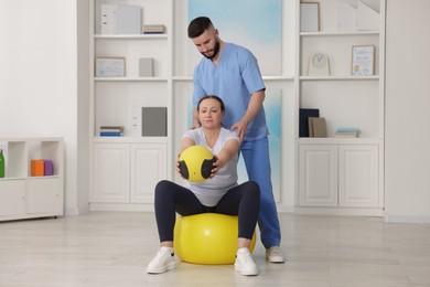 Photo of Doctor and patient exercising with medicine ball in clinic