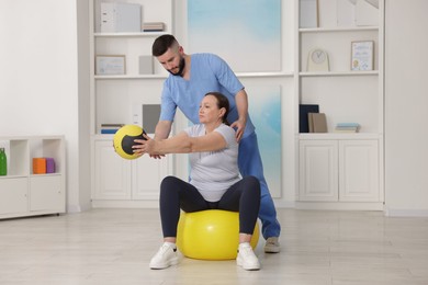 Photo of Doctor and patient exercising with medicine ball in clinic