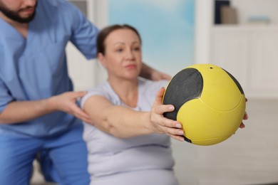 Photo of Doctor and patient exercising with medicine ball in clinic, selective focus