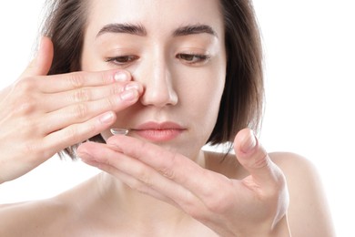 Photo of Woman putting in contact lens on white background, closeup