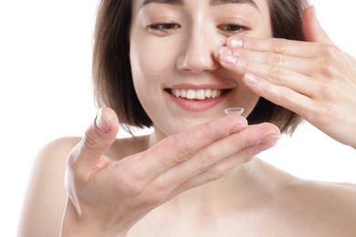 Photo of Woman putting in contact lens on white background, closeup
