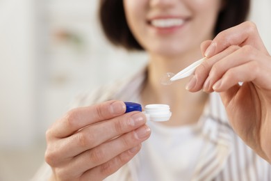 Photo of Woman taking contact lens out of case indoors, closeup