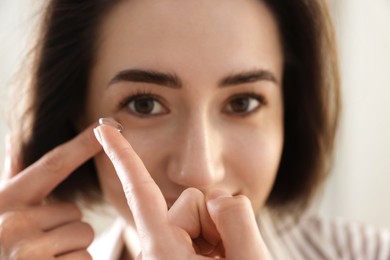 Photo of Beautiful woman putting in contact lens indoors, closeup