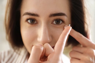 Photo of Beautiful woman putting in contact lens indoors, closeup