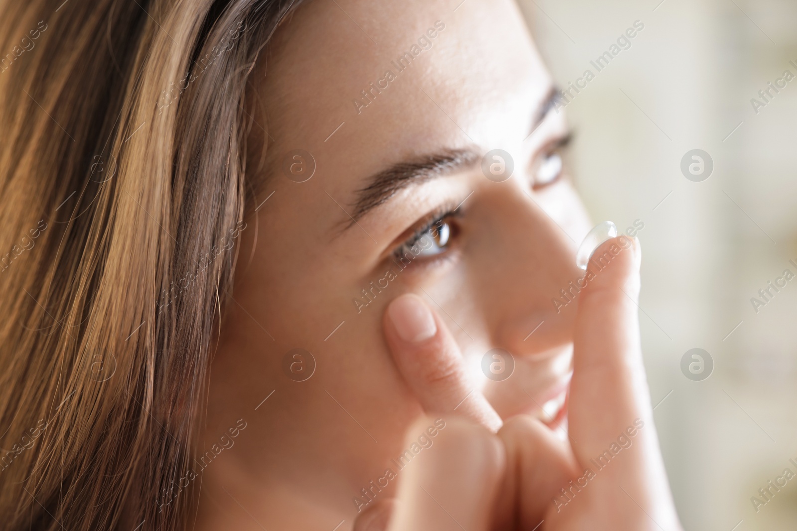 Beautiful woman putting in contact lens indoors, closeup Photo of Beautiful woman putting in contact lens indoors, closeup