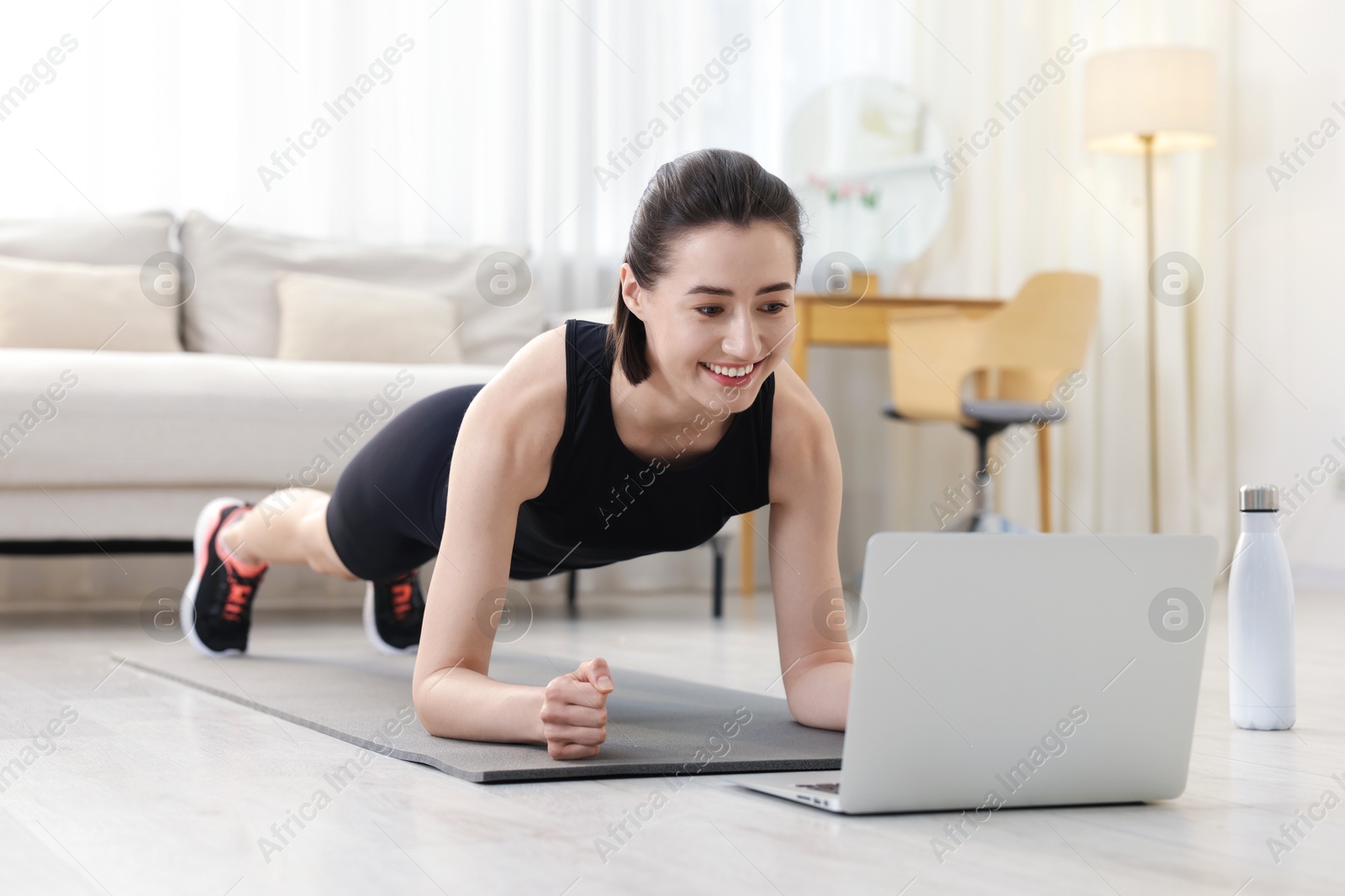 Woman doing plank exercise during online class with coach at home. Sport and healthy lifestyle Photo of Woman doing plank exercise during online class with coach at home. Sport and healthy lifestyle