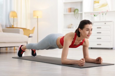 Photo of Woman doing plank exercise at home. Sport and healthy lifestyle