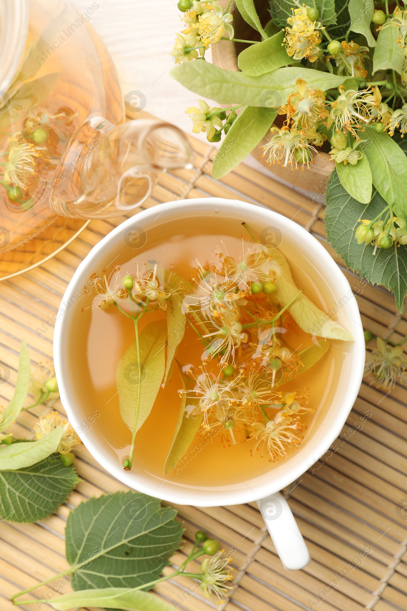 Fresh linden tea in cup, teapot and flowers on white wooden table, flat lay Photo of Fresh linden tea in cup, teapot and flowers on white wooden table, flat lay