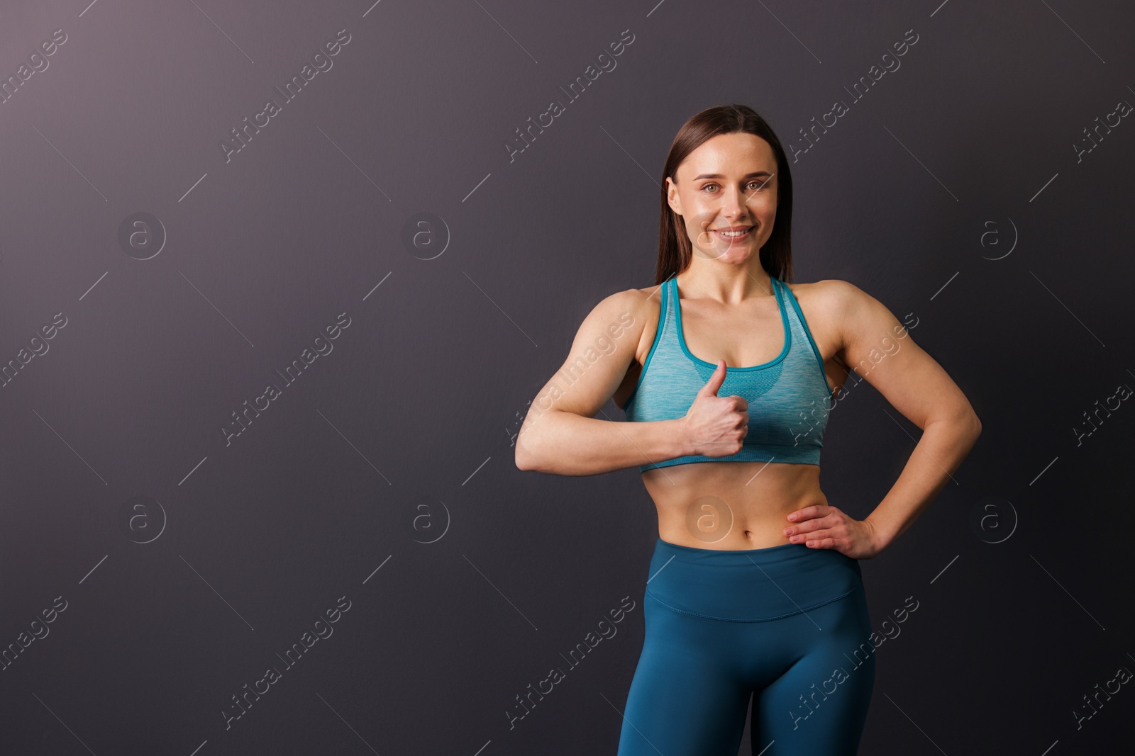 Portrait of professional trainer showing thumbs up on black background. Space for text Photo of Portrait of professional trainer showing thumbs up on black background. Space for text