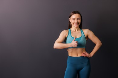 Photo of Portrait of professional trainer showing thumbs up on black background. Space for text
