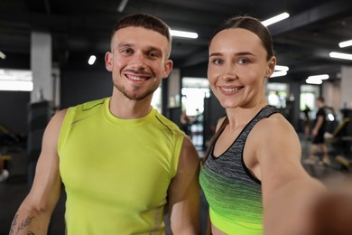 Photo of Happy personal trainers taking selfie in gym