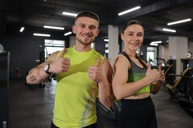 Photo of Personal trainers showing thumbs ups in gym