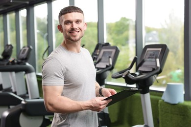 Photo of Professional personal trainer with clipboard in gym