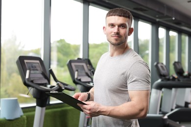 Photo of Professional personal trainer with clipboard in gym