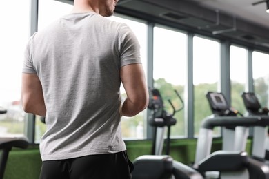 Photo of Personal trainer in sport center, back view