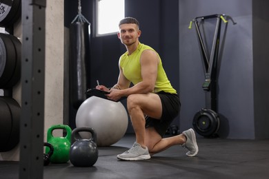 Photo of Personal trainer with clipboard and sports equipment in gym