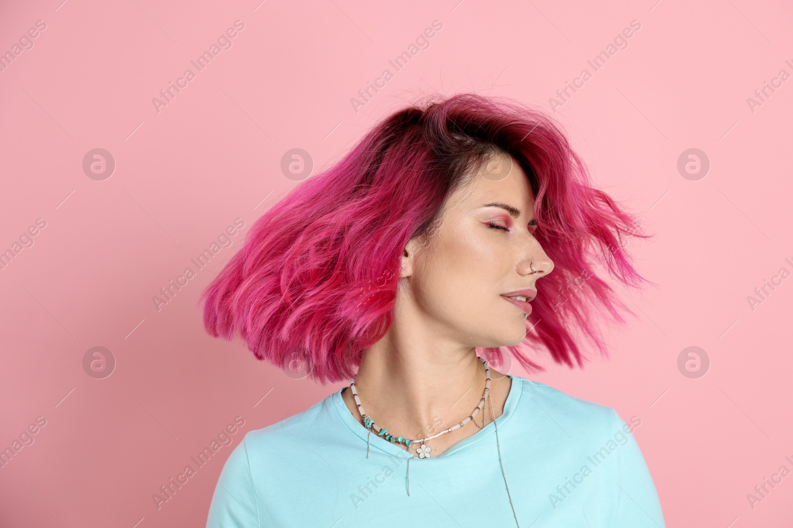 Beautiful woman with bright dyed hair shaking head on pink background Photo of Beautiful woman with bright dyed hair shaking head on pink background