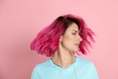 Photo of Beautiful woman with bright dyed hair shaking head on pink background