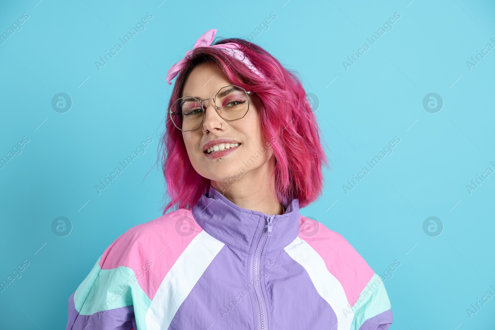 Beautiful woman with pink dyed hair in glasses on light blue background Photo of Beautiful woman with pink dyed hair in glasses on light blue background