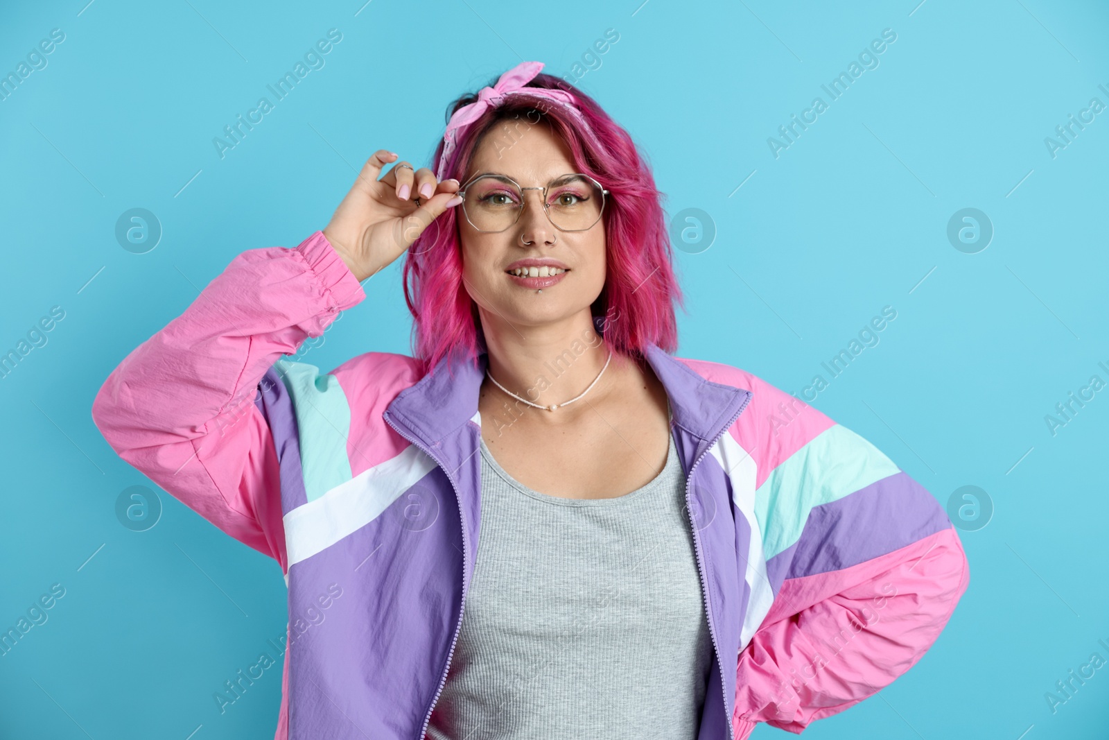 Beautiful woman with pink dyed hair in glasses on light blue background Photo of Beautiful woman with pink dyed hair in glasses on light blue background