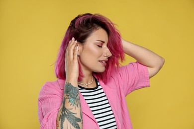 Photo of Beautiful woman with pink dyed hair on yellow background