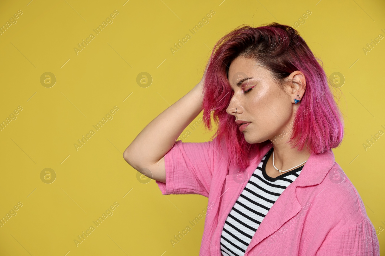 Beautiful woman with pink dyed hair on yellow background, space for text Photo of Beautiful woman with pink dyed hair on yellow background, space for text