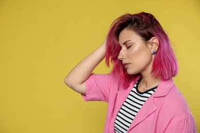 Photo of Beautiful woman with pink dyed hair on yellow background, space for text
