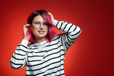 Photo of Beautiful woman with pink dyed hair in glasses on red gradient background