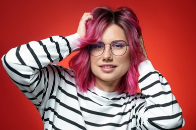Photo of Beautiful woman with pink dyed hair in glasses on red gradient background