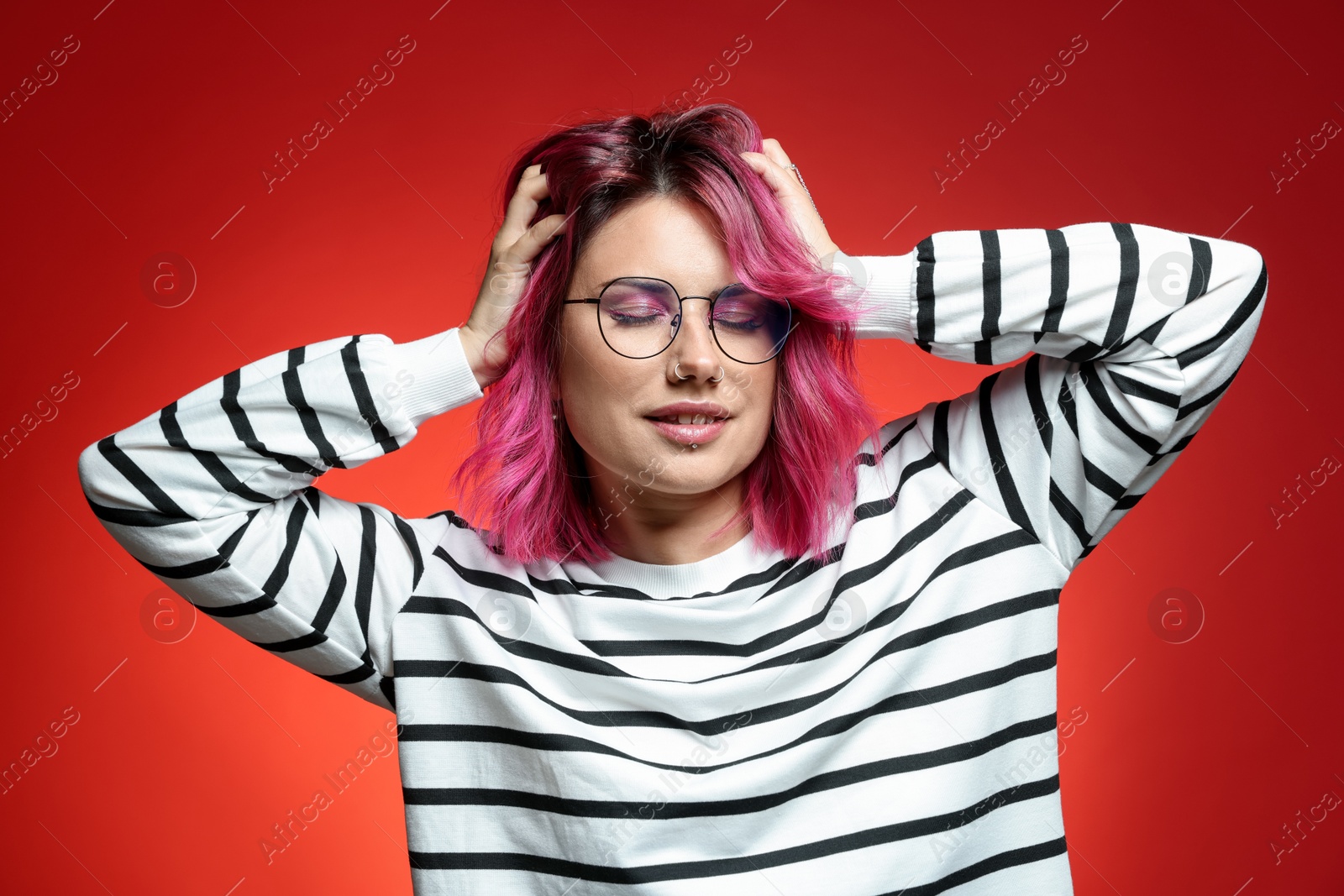 Beautiful woman with pink dyed hair in glasses on red gradient background Photo of Beautiful woman with pink dyed hair in glasses on red gradient background