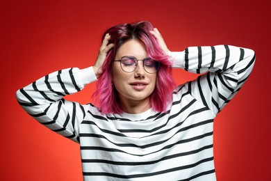 Photo of Beautiful woman with pink dyed hair in glasses on red gradient background