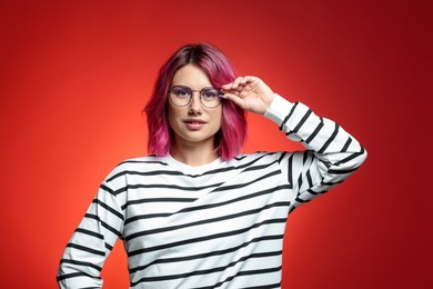 Photo of Beautiful woman with pink dyed hair in glasses on red gradient background