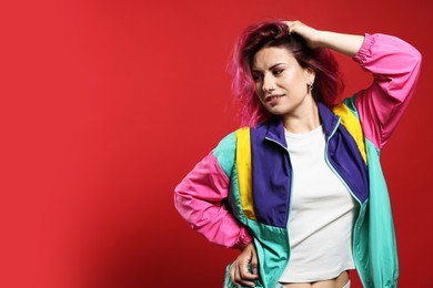 Photo of Beautiful woman with pink dyed hair on red background, space for text