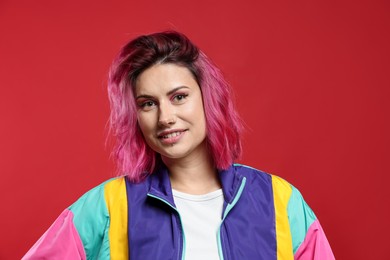 Photo of Beautiful woman with pink dyed hair on red background