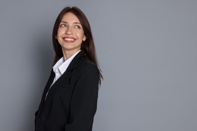 Photo of Happy woman in suit on grey background, space for text