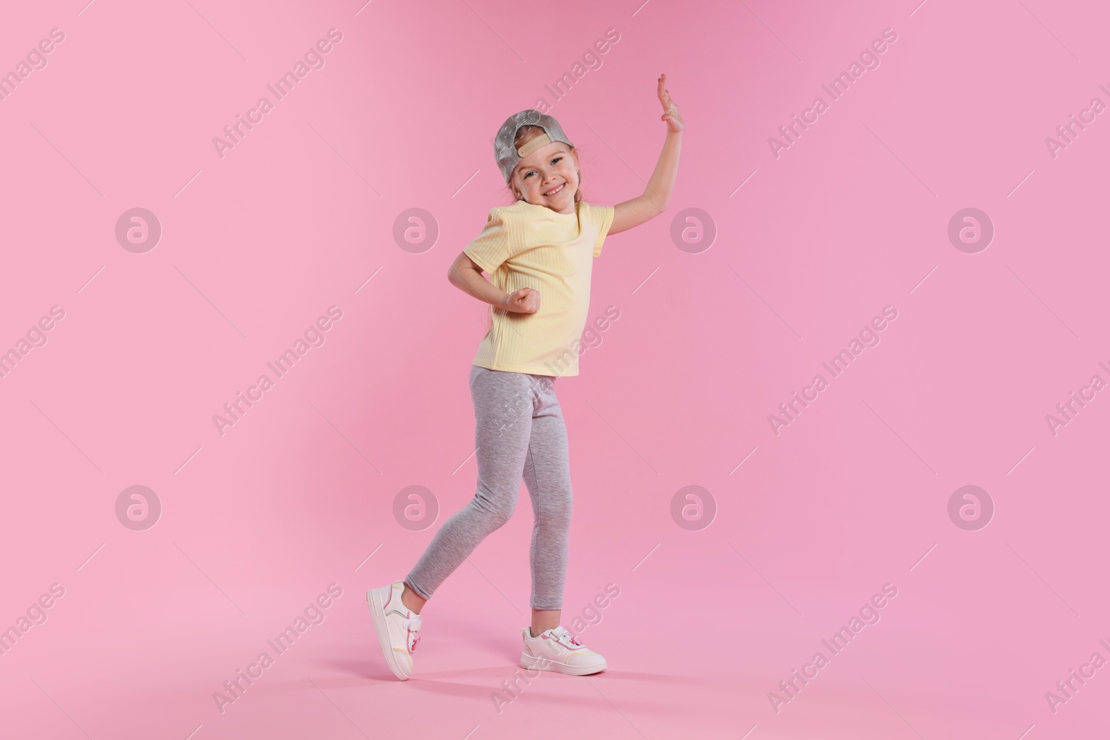 Cute little girl dancing on pink background Photo of Cute little girl dancing on pink background