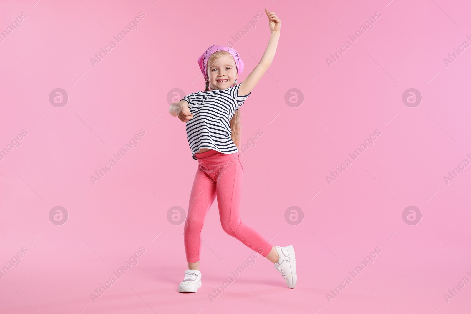 Cute little girl dancing on pink background Photo of Cute little girl dancing on pink background