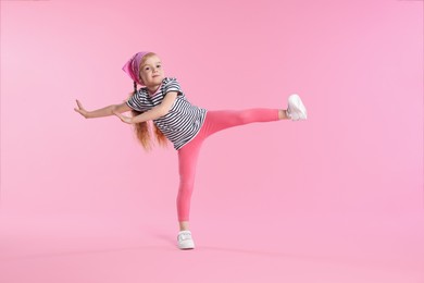 Photo of Cute little girl dancing on pink background