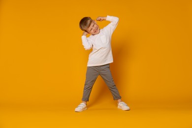 Photo of Happy little boy dancing on orange background