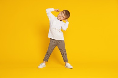 Photo of Happy little boy dancing on orange background