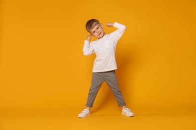 Photo of Happy little boy dancing on orange background