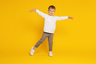 Photo of Happy little boy dancing on orange background