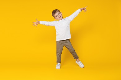 Photo of Happy little boy dancing on orange background