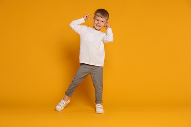 Photo of Happy little boy dancing on orange background